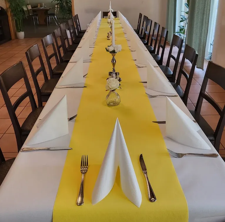 Lange festliche Tafel mit gelbem Tischläufer, weißen Servietten-Fächern und Kerzen
