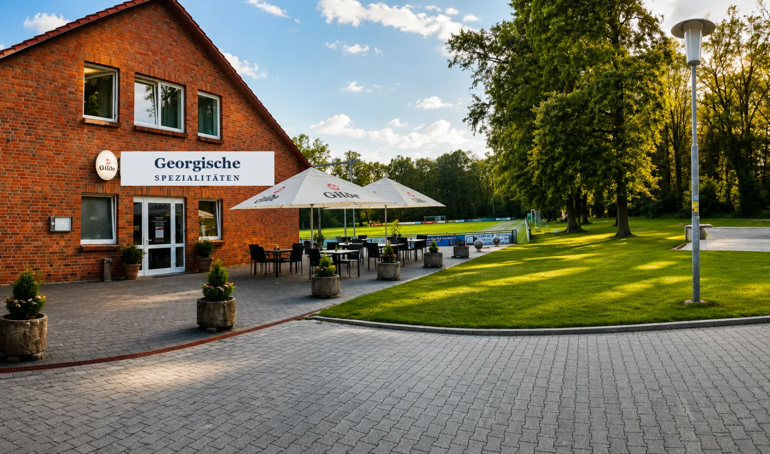 Unser Restaurant in Parsau: Backsteinhaus mit Terrasse, Sonnenschirmen und viel Grün ringsum